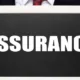Personne en costume tenant une ardoise sur laquelle est écrit Assurance