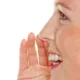Jeune femme de profil, une main près de la bouche, qui murmure un secret en souriant