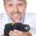 Homme souriant en blouse blanche tenant une perceuse devant lui