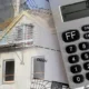 Immeuble en construction avec échafaudage, calculatrice et plan de maison au premier plan