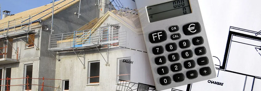 Immeuble en construction avec échafaudage, calculatrice et plan de maison au premier plan