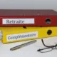 Classeurs rouge Retraite et jaune Complémentaire avec un stylo et des lunettes